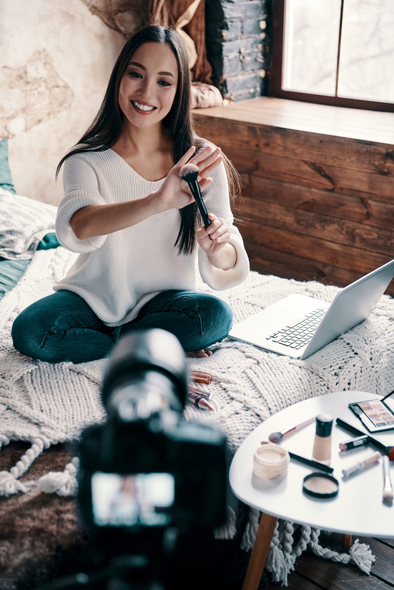 Giving advice. Top view of beautiful young woman holding makeup brush and smiling while making social media video