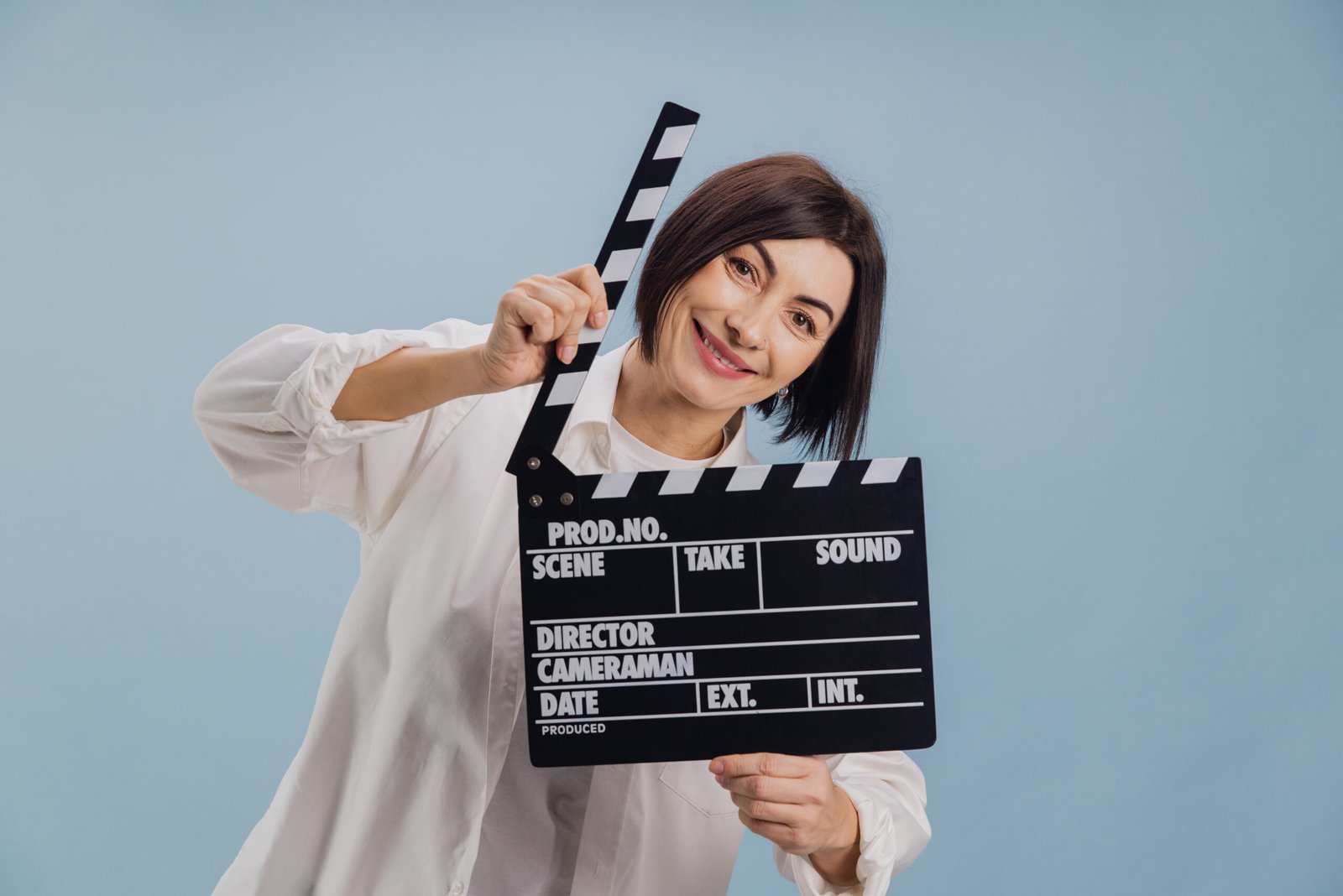 Cheerful mature woman director holding a clapperboard, ready to start filming a new scene on a movie set